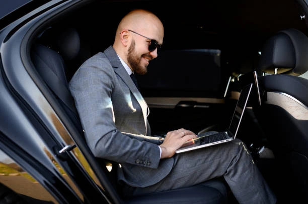Taxi Skopje Black Car Private Transfer Service Business traveler working on a laptop in the back seat of a luxury private transfer vehicle